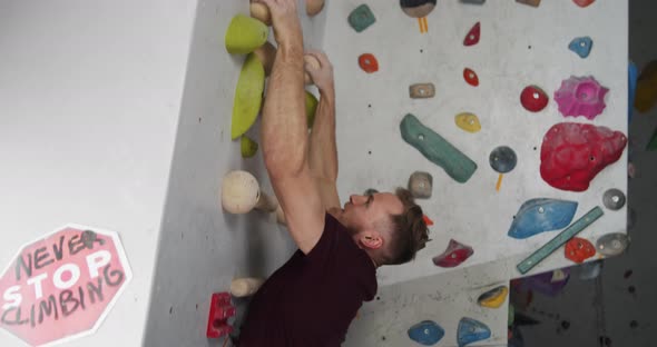 Young Bearded Athlete Warming Up Arms Before Training on a Climbing Wall