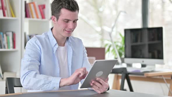 Cheerful Young Man Using Tablet Pc in Office