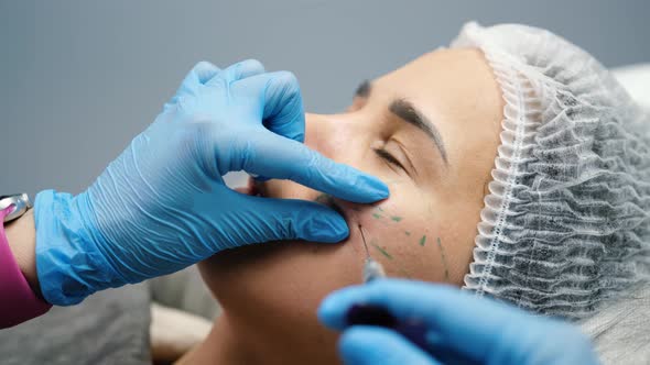 Beautician Makes Injections on the Face of a Young Woman Client in the Area Around the Eyes Closeup