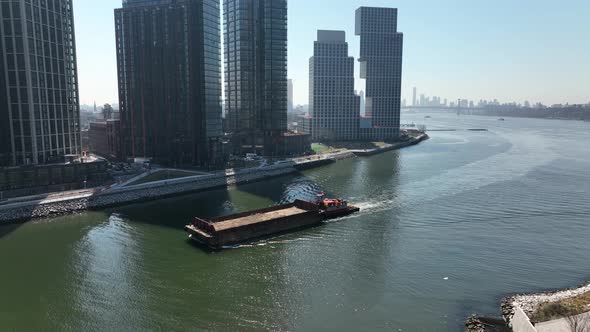 An aerial view of a barge sailing down Newtown Creek with new high-rise apartment buildings in Brook