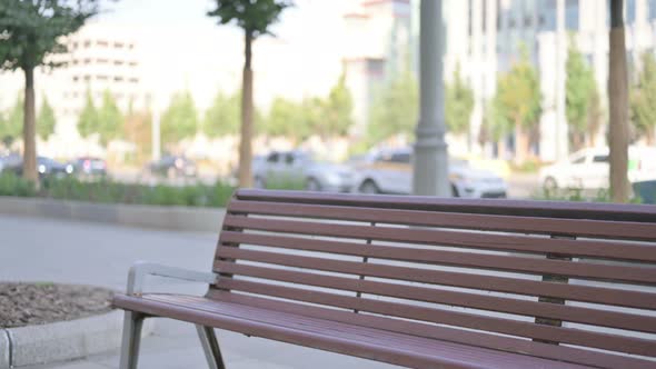 Young Adult Man Coming and Sitting on Bench Outdoor