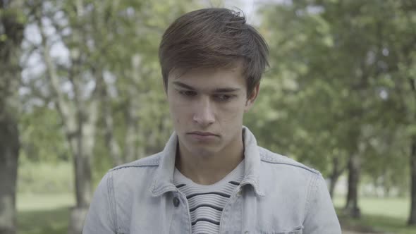 Depressed Stressed Brunette Man Standing Outdoors on Summer Day