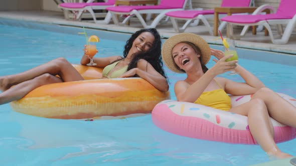Two Multiracial People Caucasian and Hispanic Tanning Women in Swimsuit Sunbathing Sitting in Tube