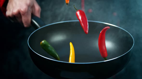 Super Slow Motion Shot of Chef Holding Frying Pan and Falling Chilli Peppers at 1000Fps.