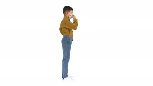 Little Boy Adjusting His Face Mask Looking at Camera on White Background.