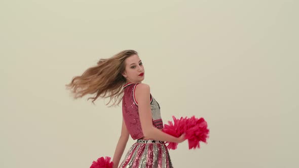 Rehearsal Dance of a Cheerleader in Uniform on a White Studio Background