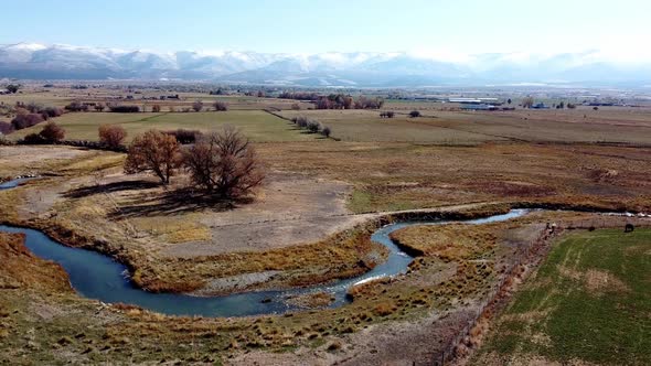 Aerial drone footage of farmland with a creek in western Utah.