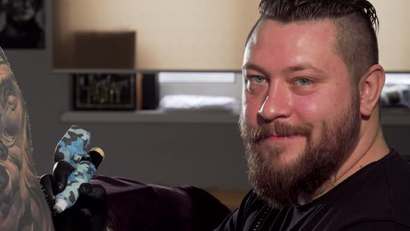 Cheerful Bearded Tattooist Smiling To the Camera While Working