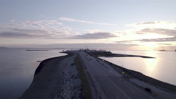 Tsawwassen ferry port in British Columbia, drone fly above highway over the ocean water during sunse