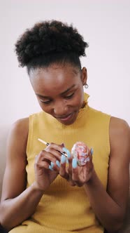 African American Young Woman Coloring Easter Egg with a Brush