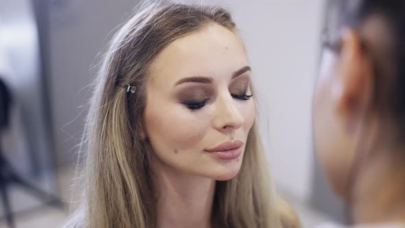 The Makeup Artist Applies the Powder to Finish Client's Makeup