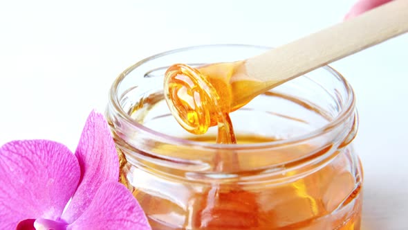 Sugar Paste or Wax Honey for Hair Removing Flows Down From Wooden Waxing Spatula Sticks Depilation