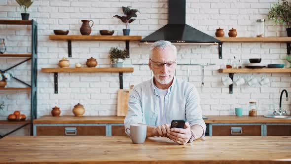 Mature Businessman Drinking Coffee Working Online on Mobile Phone or Having Rest Browsing News