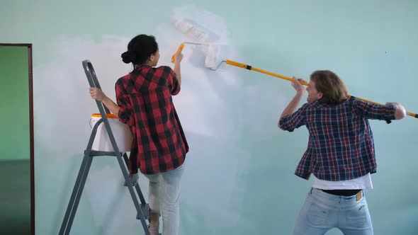 Joyful Couple Painting Interior Wall in New House