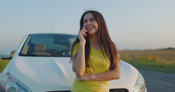 Happy Girl Talking on Phone Against Background of Car