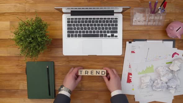 Word trend consists of wooden cubes letters on office table next to notebook.