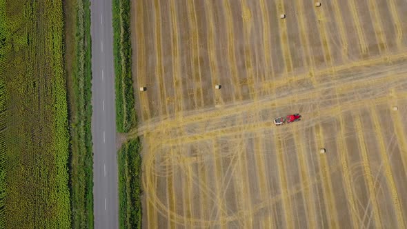 Aerial View of Haymaking Processed Into Round Bales. Red Tractor Works in the Field