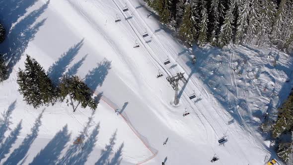 Aerial View of Ski Slopes with Skiers Go Down Under Ski Lifts on Ski Resort