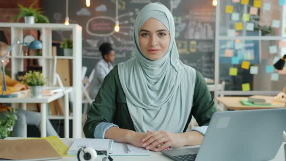 Slow Motion Portrait of Beautiful Muslim Woman in Hijab Sitting at Desk at Work