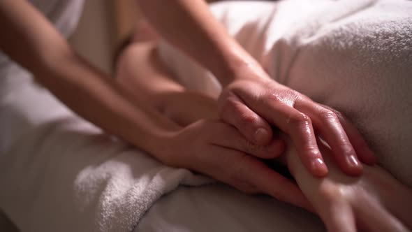 Massage Therapist Massaging the Arms Collarbone and Chest of a Relaxed Client Lying on a Sofa in a