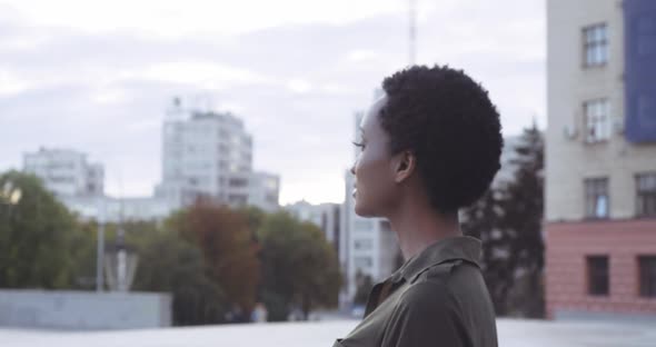 Young Attractive International Model with Stylish Hairstyle Steps Gracefully Along Street, African