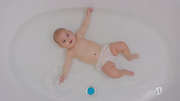 Happy Baby Bathing. Cheerful Child of Five Months Old in Water.