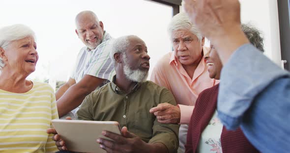 Happy senior diverse people talking and using laptop at retirement home