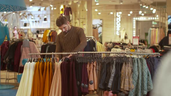 Guy Sorts Things Out on a Hanger in a Store