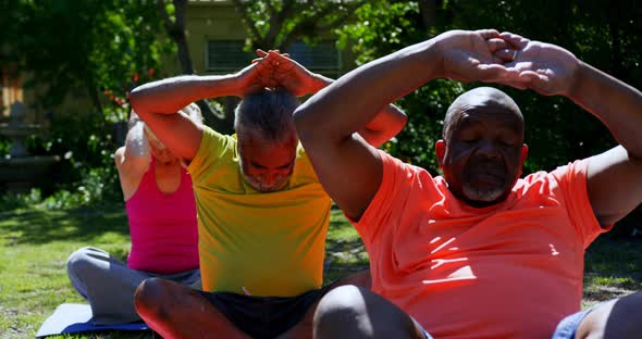 Front view of active mixed-race senior people performing yoga in the garden of nursing home 4k