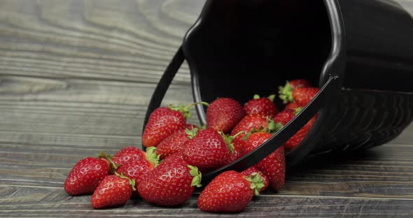 Strawberries in a Small Black Bucket on the Wooden Table - Close Up