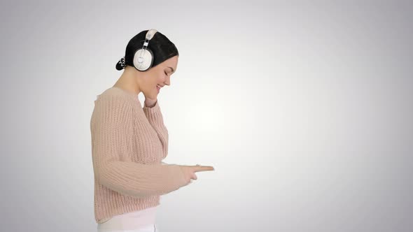 Smiling Female with Headphones Walking and Enjoying the Music on Gradient Background