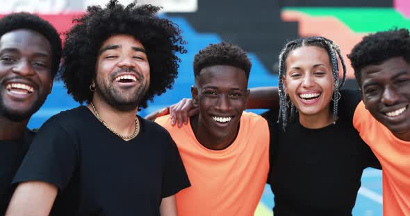 Multiracial people hugging each other in the city - Basketball team smiling on camera