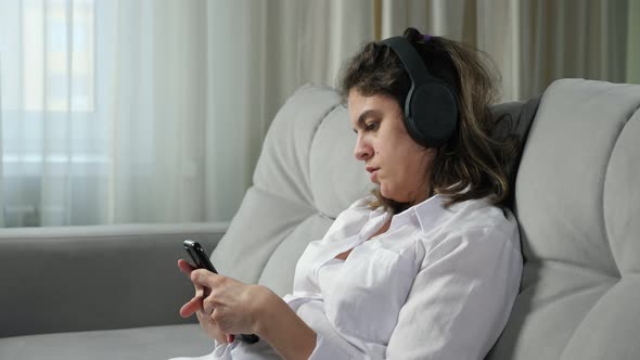 Disabled Woman in Headphones Listens to Music Holding Phone