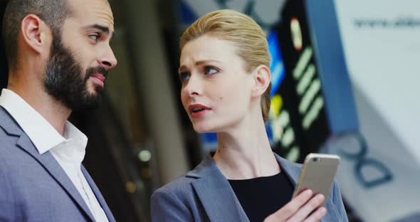 Business people discussing over smartphone