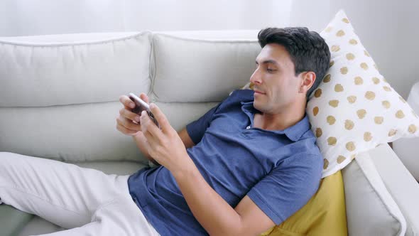 Man Lying on Couch Using Smartphone