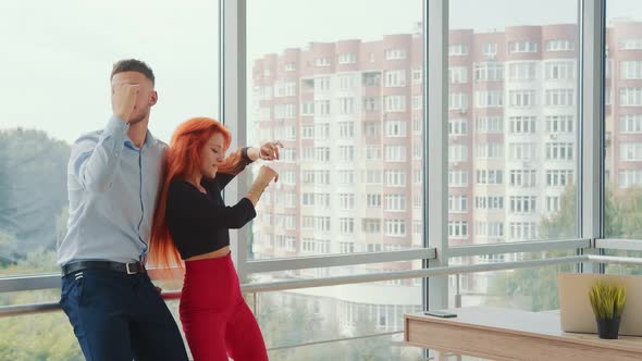 Businesspeople Dancing in the Office. Happy Woman and Man Dancing Together By the Window. Dance of