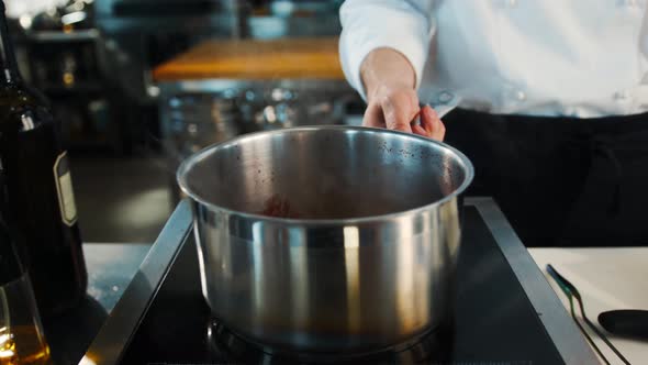 The chef makes sauce in saucepan in a professional restaurant kitchen process of food preparation