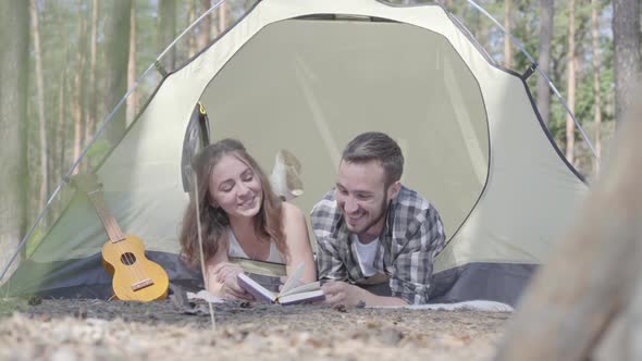 Portrait Young Man Pretty Young Woman Lying Near Each Other in the Tent in the Forest Reading the