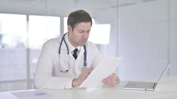 Hardworking Middle Aged Doctor Reading Documents in Office