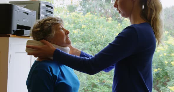 Physiotherapist put cervical collar to senior woman
