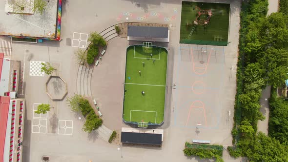 Tiny green football field in school yard in Solna, Stockholm. Aerial top down descend rotate shot