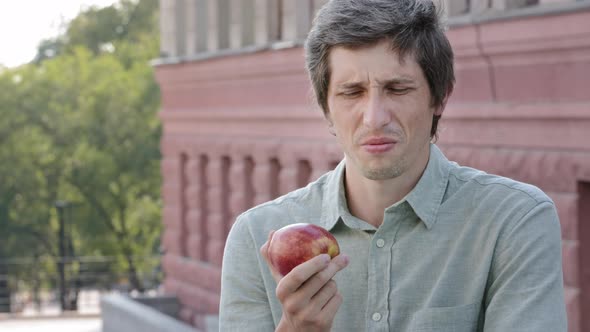 Young Adult Male Shopper Customer Wants to Eat Delicious Juicy Ripe Apple Sniffs Makes Grimace of
