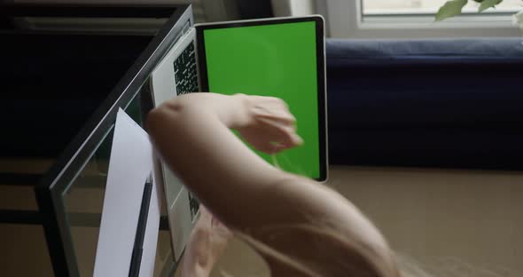 female hands open the lid of a laptop with a green screen and types on the keyboard