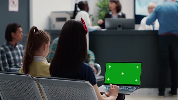 Mother and Little Girl Using Laptop with Greenscreen in Waiting Room