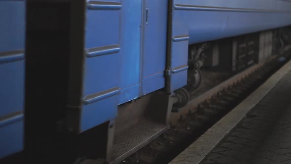 Passenger Railway Transport Passes By a Camera and Arrives at Station. Close Up Spinning Steel