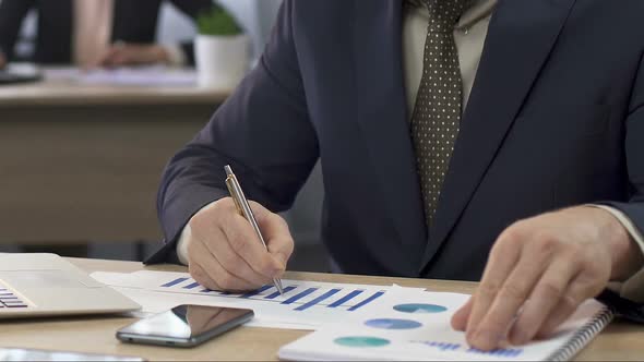 Financial Director Analyzing Two Charts and Making Notes, Businessman at Work