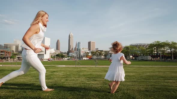 Mother and Daughter in the Park on a Running Together on Sunny Day
