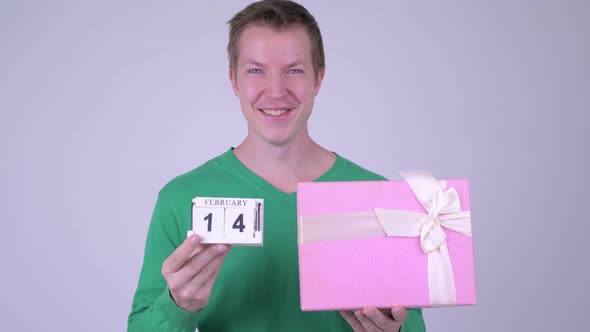 Happy Young Handsome Man with Calendar Block and Gift Box
