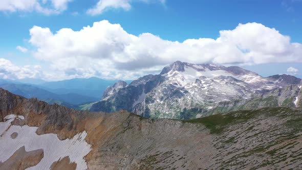 Aerial Shot of a Mountain Ridge Against Rocky Cliffs, Glacier and Snowy Peaks. Amazing Aerial View