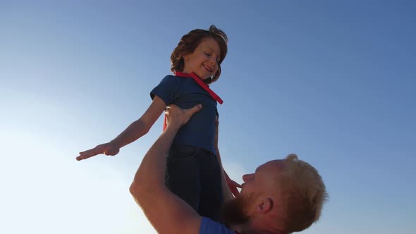 Dad Raising Son High Imitating Superhero's Flight
